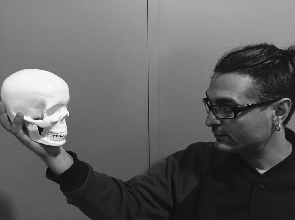 Foto en blanco y negro del tatuador Gennaro Sacco de Kaifa´s tattoo Studio Madrid, sosteniendo una calavera en la mano