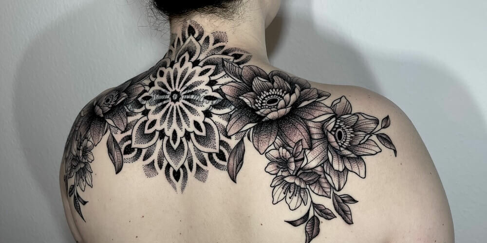 Foto de una mujer joven con un tatuaje que va de hombro a hombro por la espalda, tatuado con estilo blackwork por Carlos cuervo, tatuador de kaifa´s tattoo studio en Madrid