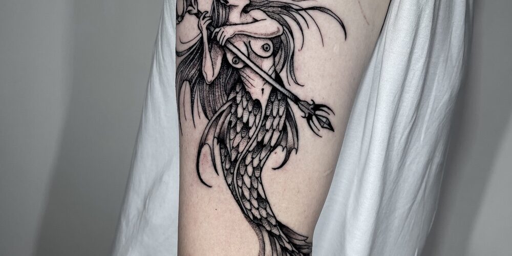 Foto de un brazo tatuado con estilo blackwork con un tatuaje de sirena por Carlos cuervo, tatuador de kaifa´s tattoo studio en Madrid